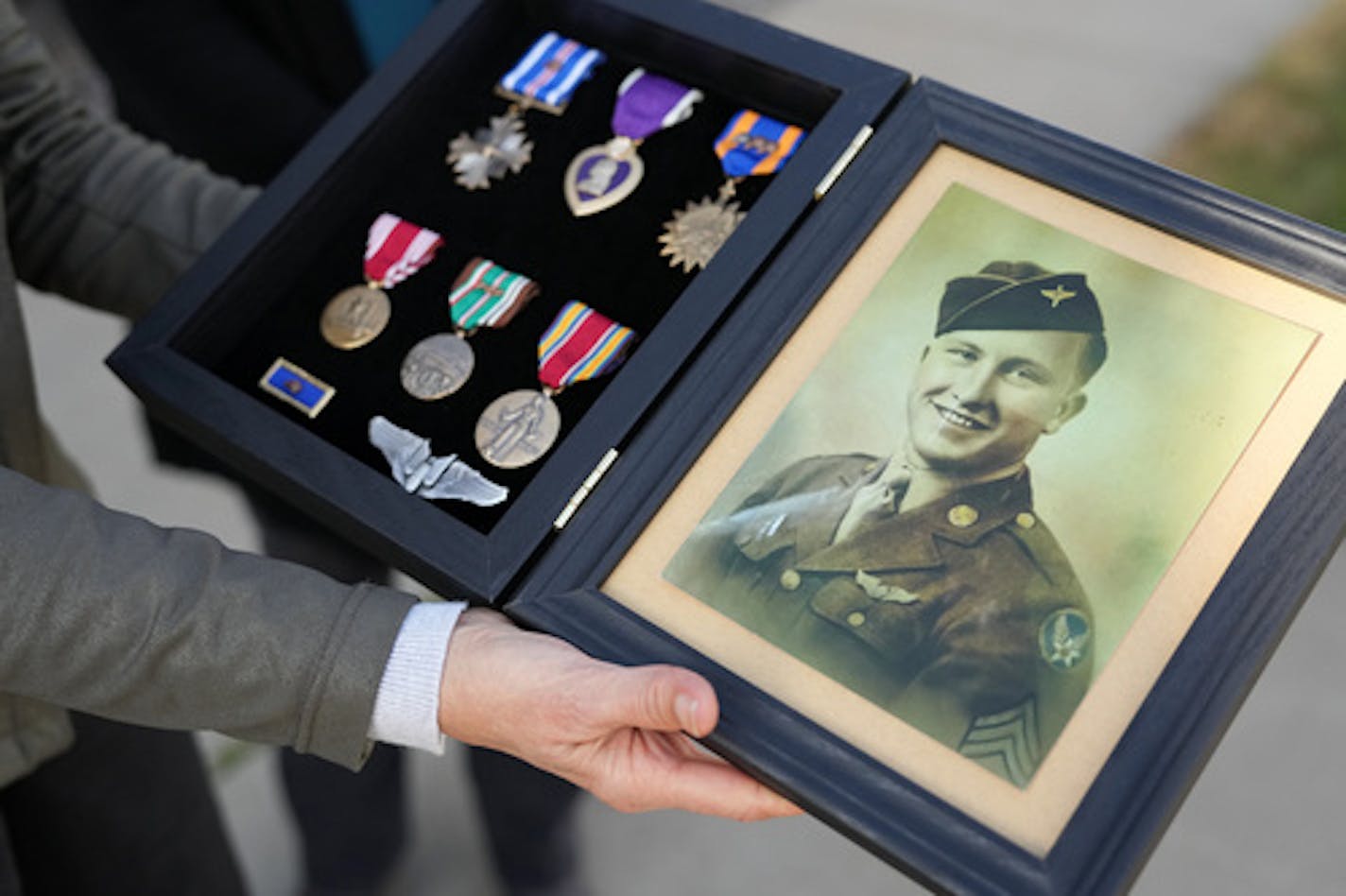 Family members of Staff Sgt. Donald Robert Duchene of St. Paul, who was killed in action on Aug. 1, 1943, while participating in a bombing raid against the oil refineries around Ploiesti, Romania during WWII dubbed Operation Tidal Wave, show a photograph of him along with replicas of his medals before receiving his remains during a military ceremony Friday, Sept. 30, 2022 at the MSP Airport Fire Station in Minneapolis. Duchene's remains were recently identified from DNA testing. He will be buried at Fort Snelling next week. ] ANTHONY SOUFFLE • anthony.souffle@startribune.com