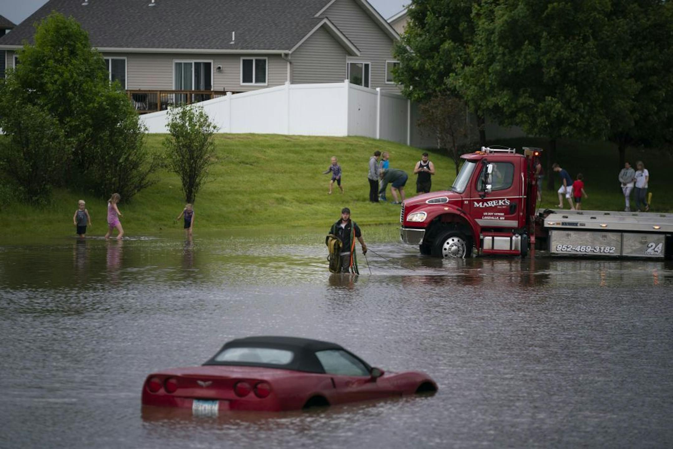 A tow truck operator brought a cable to hook up to one of three vehicles that were stranded in deep water on Dodd Boulevard next to Lakeville North High School after heavy rain Tuesday.