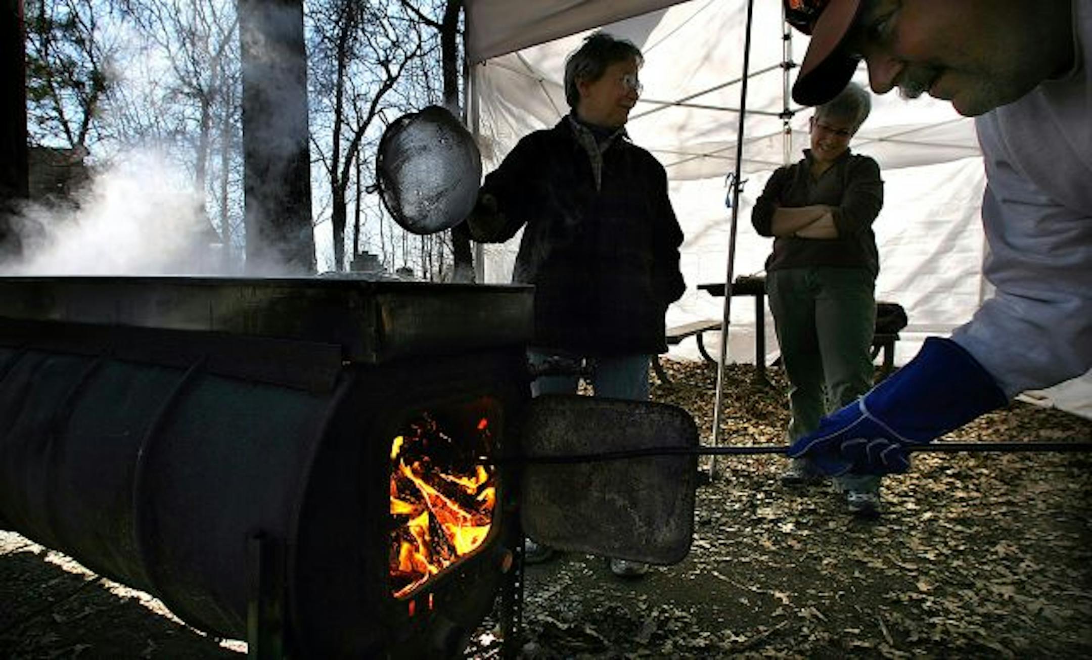 Volunteers Rita Messing, Ginny Yingling and Mike Bares boiled maple sap as part of the process to make maple syrup at Wild River State Park in Center City.