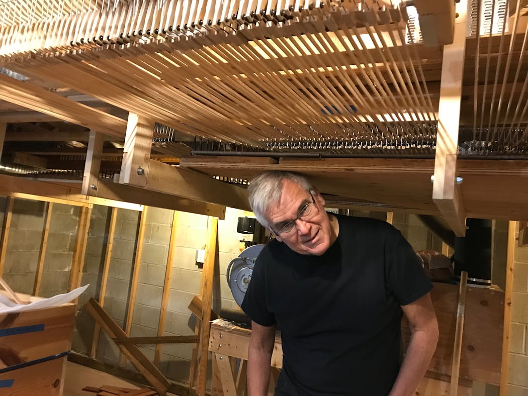 Charles Harder underneath the intricate keyboard linkage system for his pipe organ mounted in the basement of his home.