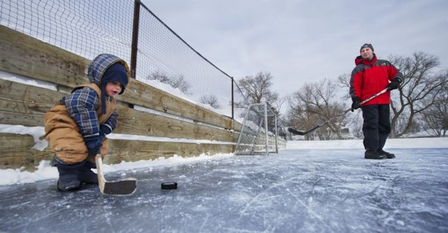 Two-year-old Varun Alter practiced hitting the puck with his dad, Mike Alter, at the Groveland Park ice rink, the most used rink in St. Paul.