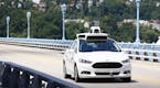 Uber employees test a self-driving Ford Fusion hybrid car.