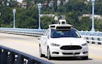 Uber employees test a self-driving Ford Fusion hybrid car.