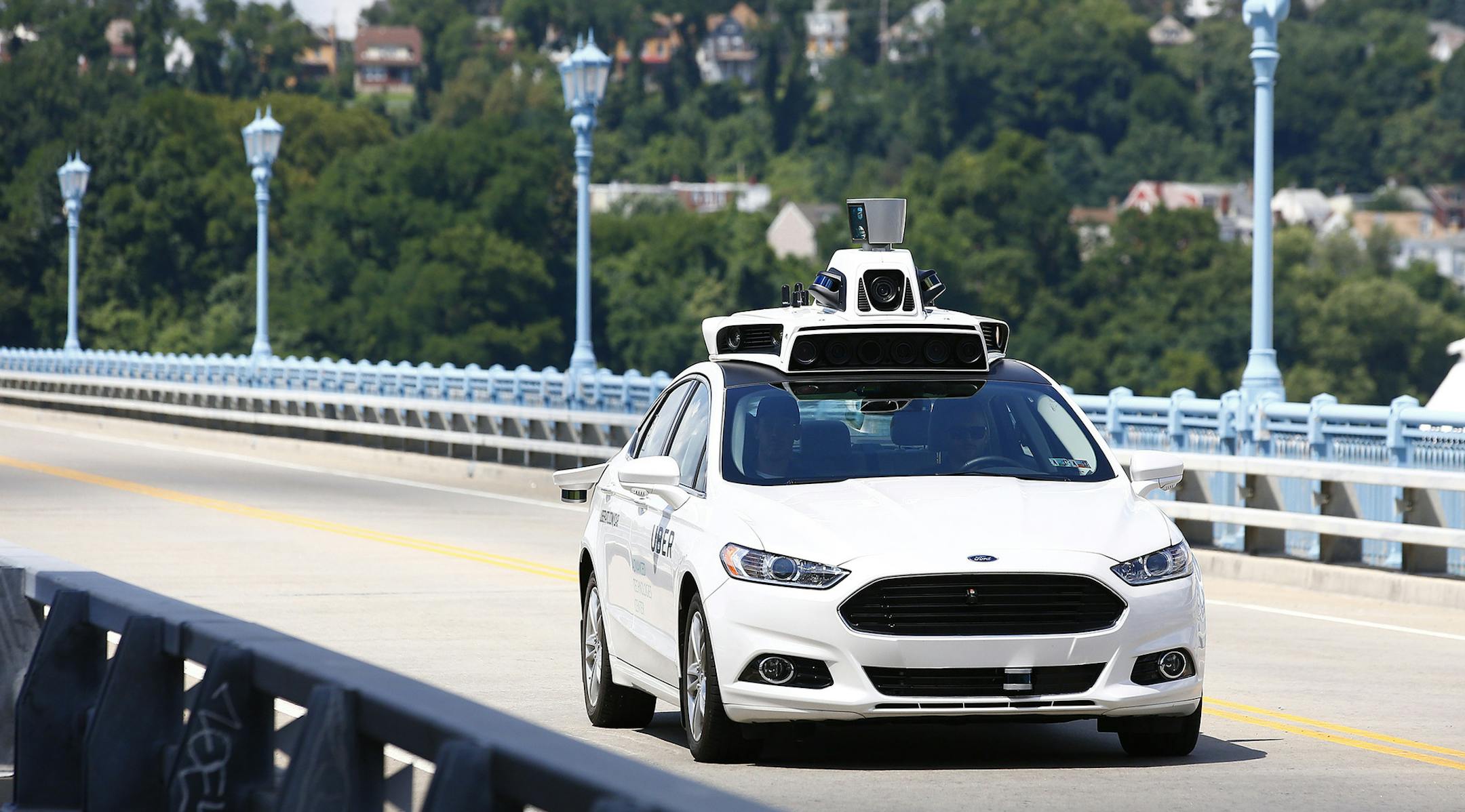 Uber employees test a self-driving Ford Fusion hybrid car.