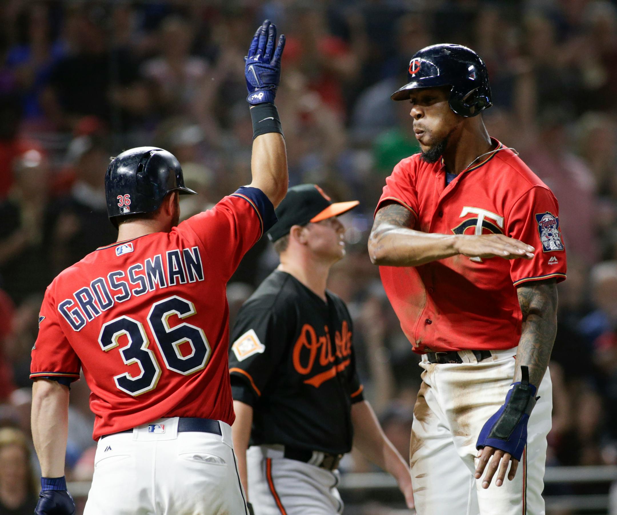 Minnesota Twins' Byron Buxton celebrates with teammate Robbie Grossman after he scored from first on a Brian Dozier single during the eighth inning of a baseball game against the Baltimore Orioles, Friday, July 7, 2017, in Minneapolis. Minnesota won 9-6. (AP Photo/Paul Battaglia)