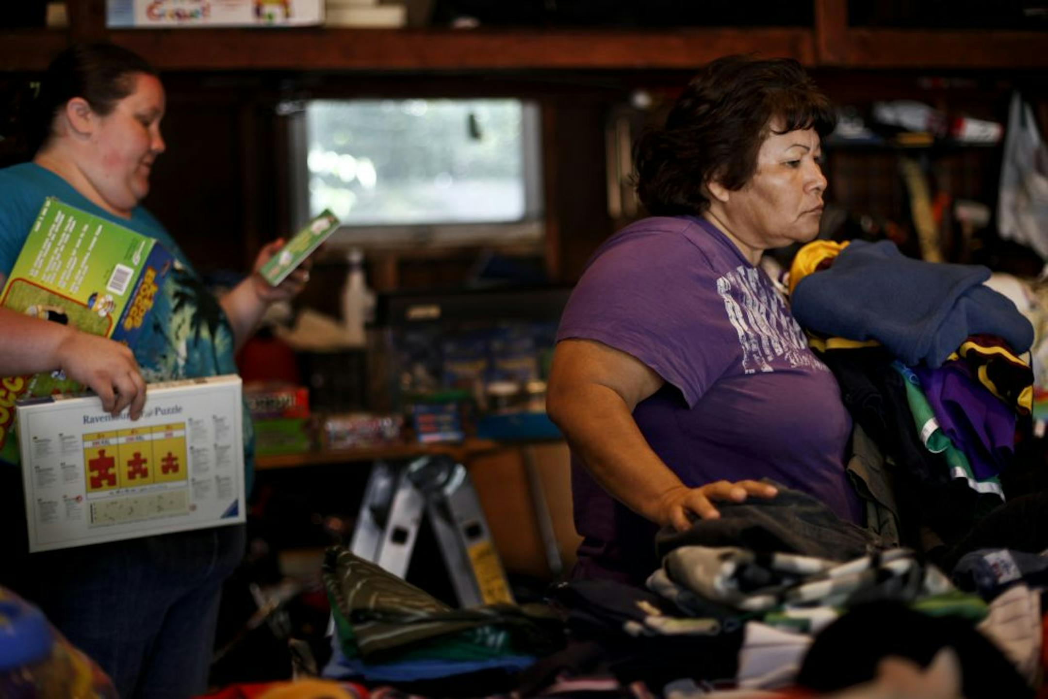 Maria Meza glances around for more clothes to add to her pile at a garage sale in Edina, Minn. on Friday, Aug. 10, 2012.