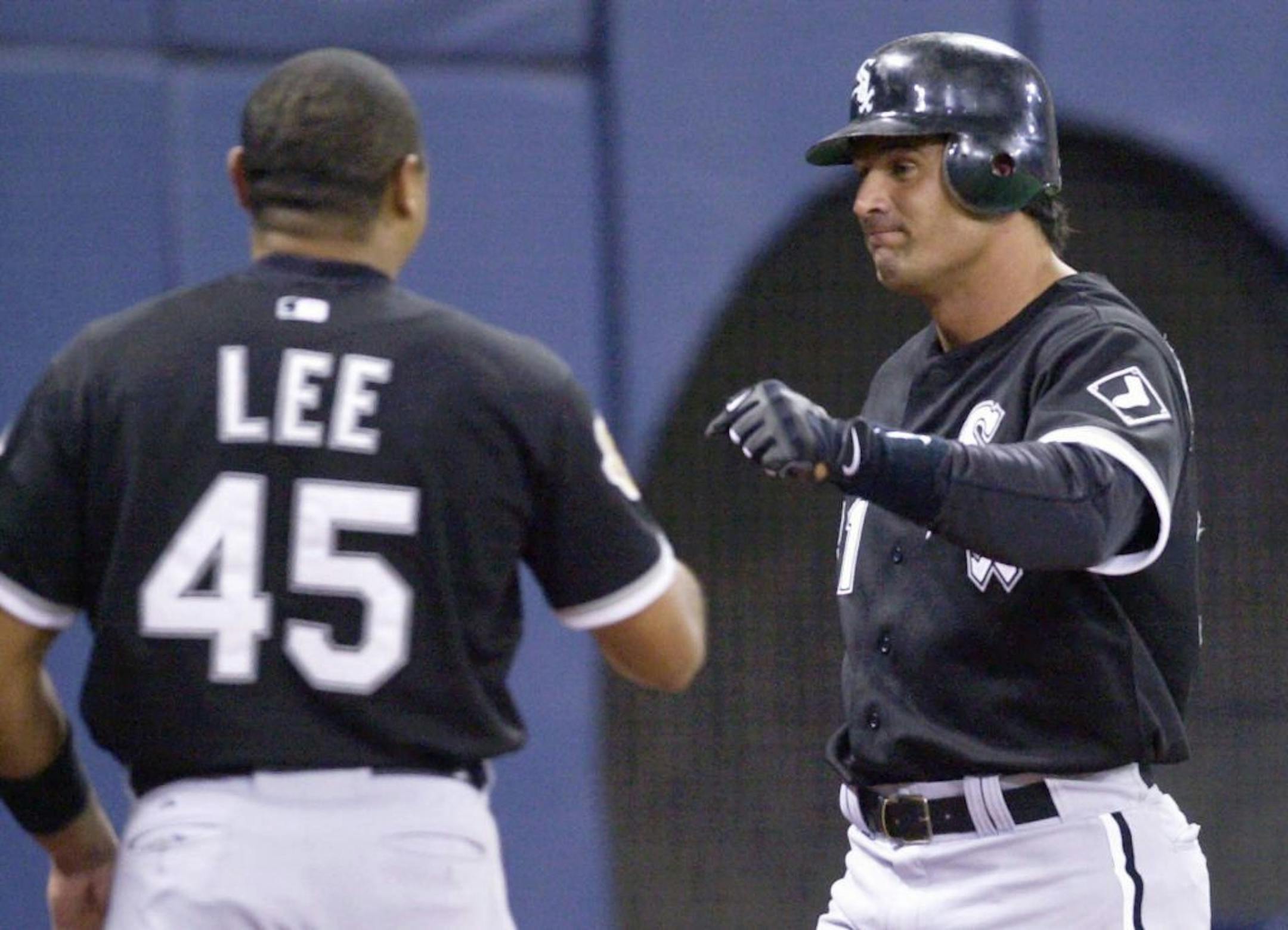 Carlos Lee (45) congratulates teammate Jose Canseco at the Metrodome in 2001.