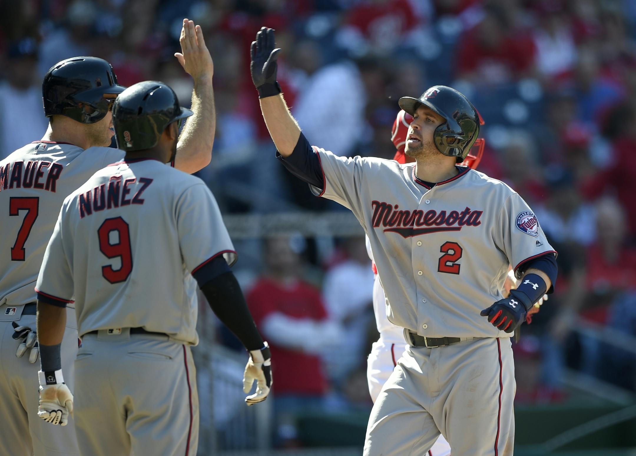 Minnesota Twins' Brian Dozier (2) celebrates a three-run home run with Joe Mauer (7) and Eduardo Nunez (9).