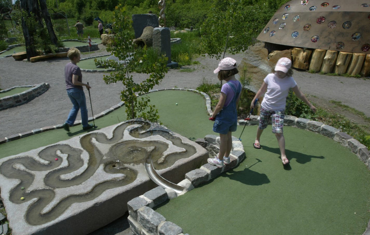 joel koyama&#xef;jkoyama@startribune.com minigolf0615 00003209a] After Melinda Pfohl drove her ball on the 13th and last hole, Gently down the stream, Ellie (10 pink shirt) and her sister Lizzy (7) Pfohl of Mound, Mn watch their ball float to the end of the water sculpture. Bruce Stillman owns Bigstone mini golf and Sculpture gardens is the newest miniature-golf course in Minnetrista. The Big Stone course is built around objects d&#xed;art, and really good ones at that.