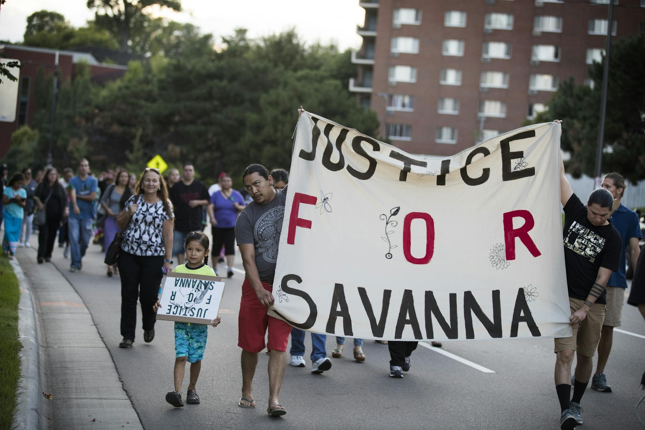 People holding banners march down University Avenue toward the Ramsey County Medical Examiner's office before a prayer circle for Savanna LaFontaine-Greywind.