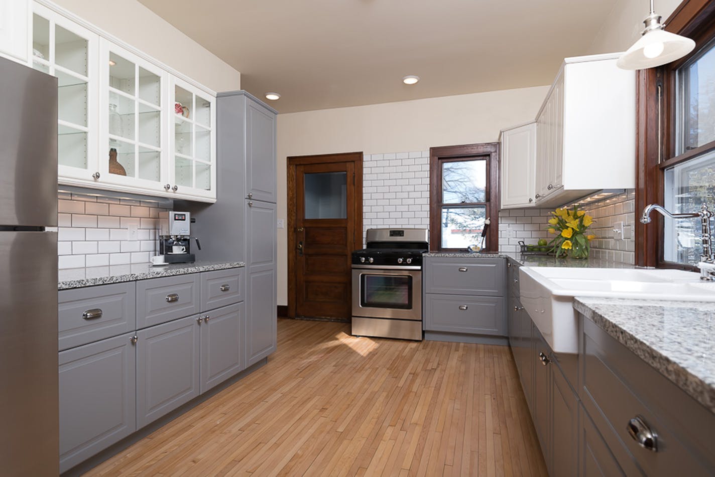 The new kitchen combines gray and white cabinets, granite countertops and original wood flooring.