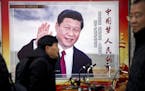 People walk past a propaganda billboard showing Chinese President Xi Jinping along a street in Beijing, Friday, March 2, 2018. The annual meetings of 