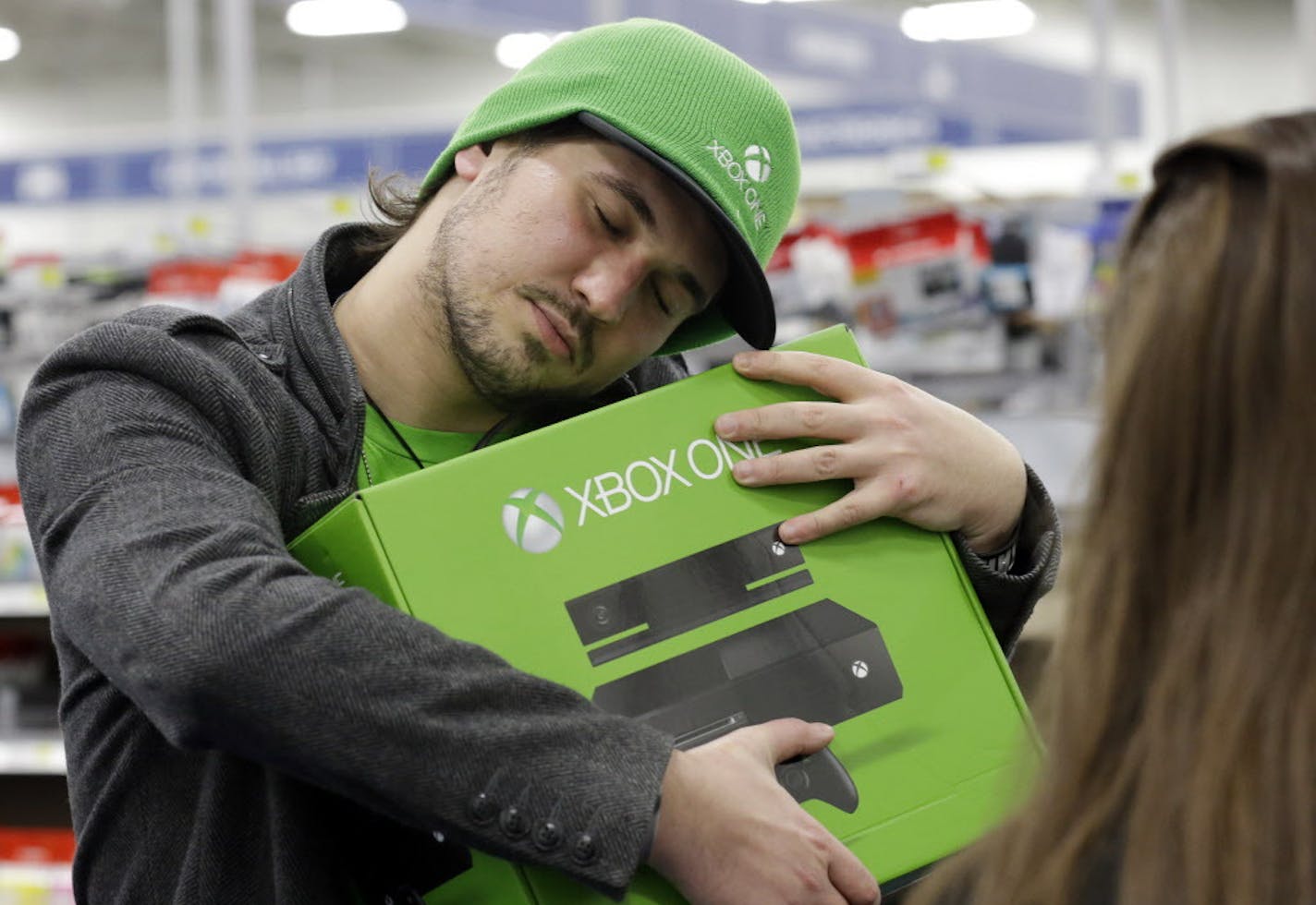 Emanuel Jumatate, from Chicago, hugs his new Xbox One after he purchased it at a Best Buy on Friday, Nov. 22, 2013, in Evanston, Ill. Microsoft is billing the Xbox One, which includes an updated Kinect motion sensor, as an all-in-one entertainment system rather than just a gaming console. (AP Photo/Nam Y. Huh)