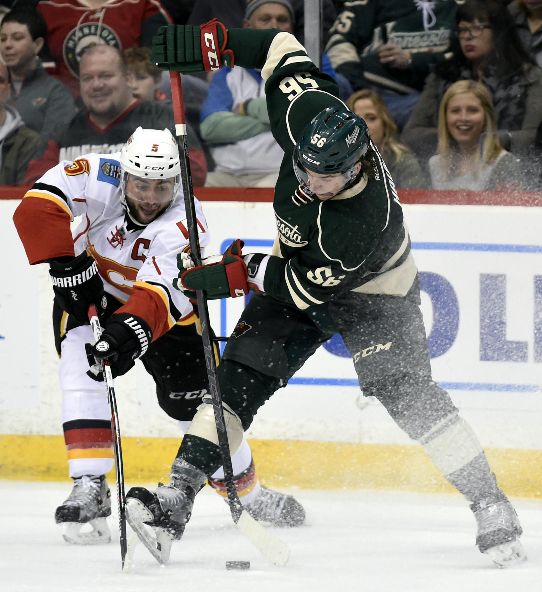 Calgary Flames' Mark Giordano, left, passes the puck away from Minnesota Wild's Erik Haula, of Finland, during the second period of an NHL hockey game Saturday, April 9, 2016, in St. Paul, Minn. (AP Photo/Hannah Foslien)