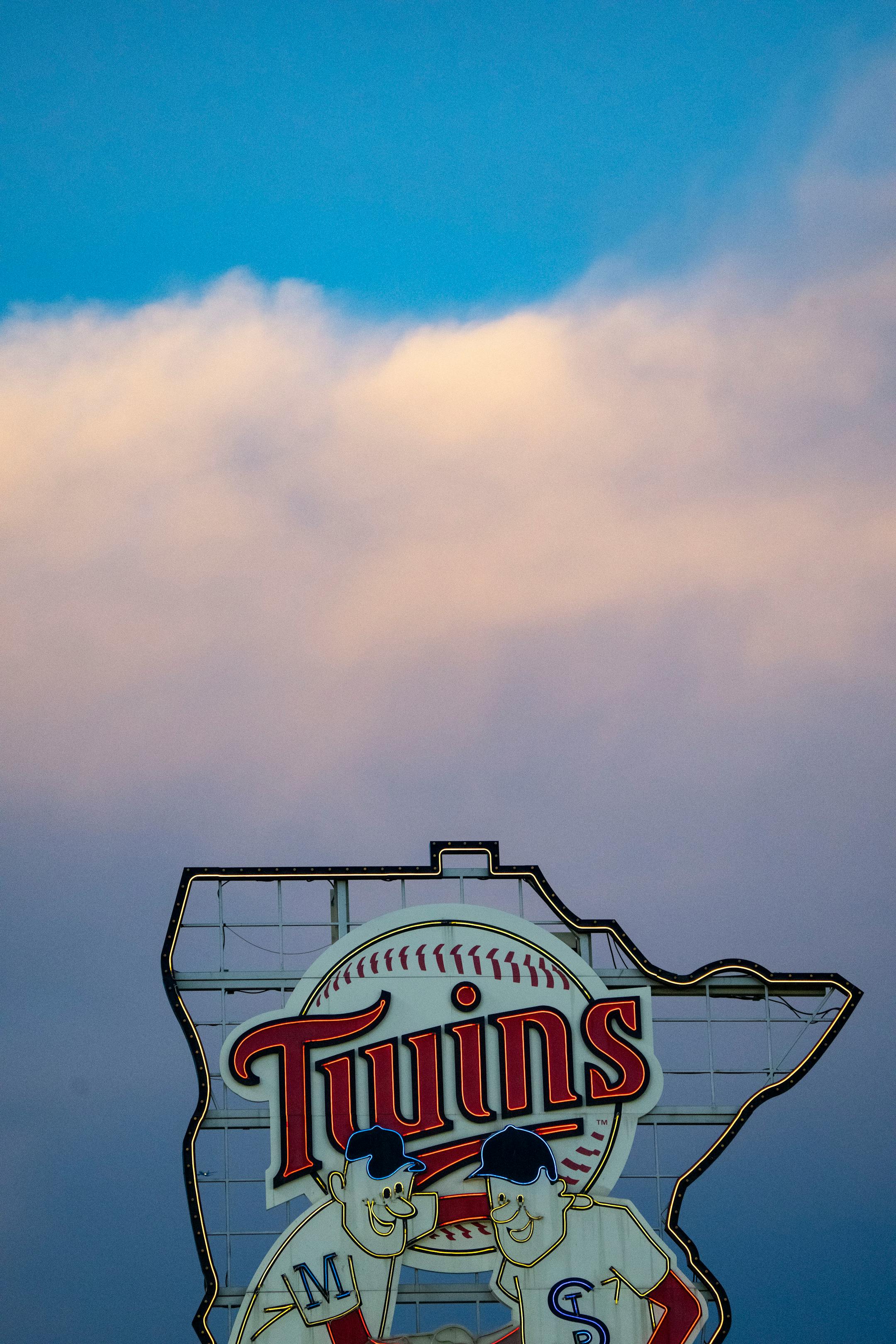 The Minnesota Twins sign is illuminated during sunset.