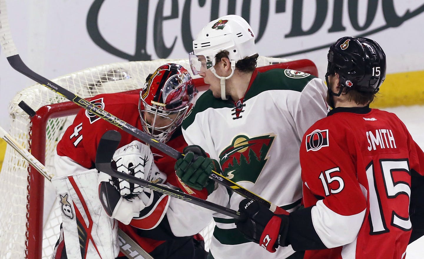 Minnesota Wild's Charlie Coyle, middle, and Ottawa Senators goaltender Craig Anderson (41) watch a loose puck as Senators' Zak Smith (15) defends during the second period of an NHL hockey game Tuesday, March 15, 2016, in Ottawa, Ontario. (Fred Chartrand/The Canadian Press via AP)