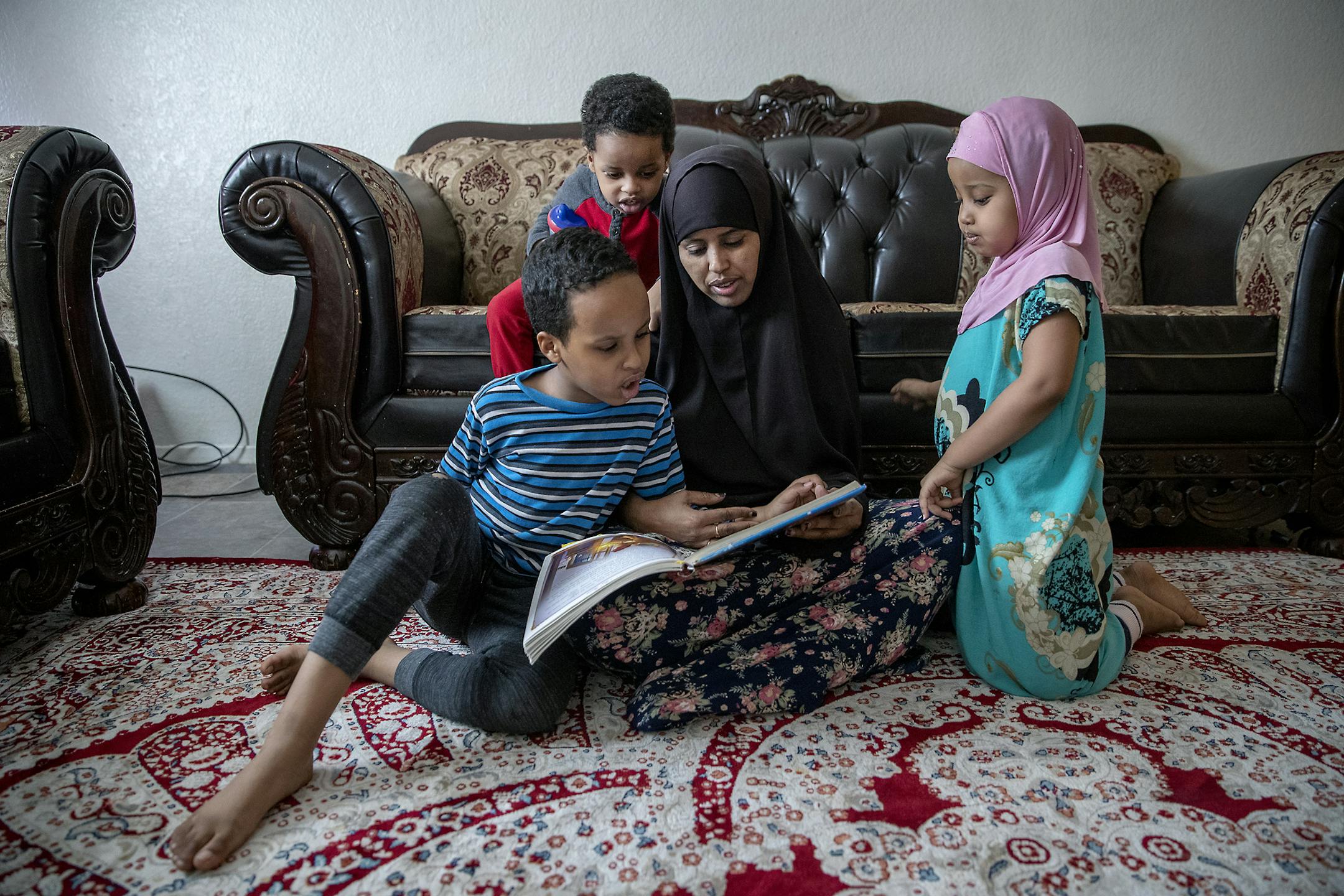 Fardowsa Bashir sat with her children, Saadiq Dahir, 6, left, Sadri, 2, center, and Anzal, 3, right, as she listened to them read to her in her home, on Feb. 6 in Minneapolis.