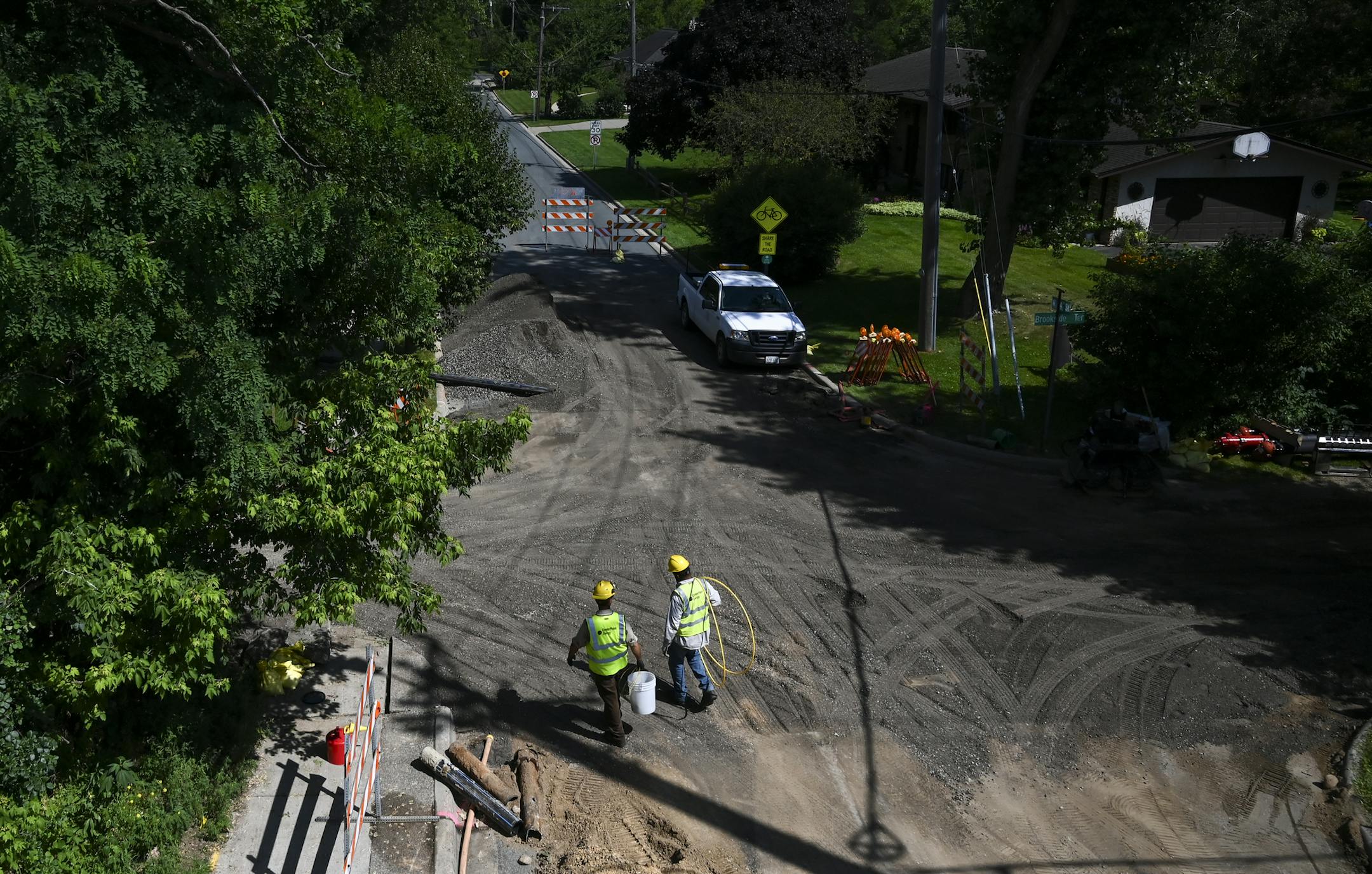 Utility workers with Centerpoint Energy walked toward the site of utility upgrades on Brookside Terrace on Tuesday.
