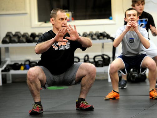 Patrick Landry, a certified CrossFit instructor, shows the proper way to do squats. Landry is one of only a handful instructors certified to teach CrossFit to children. (John Heller/Pittsburgh Post-Gazette/TNS) ORG XMIT: 1165717