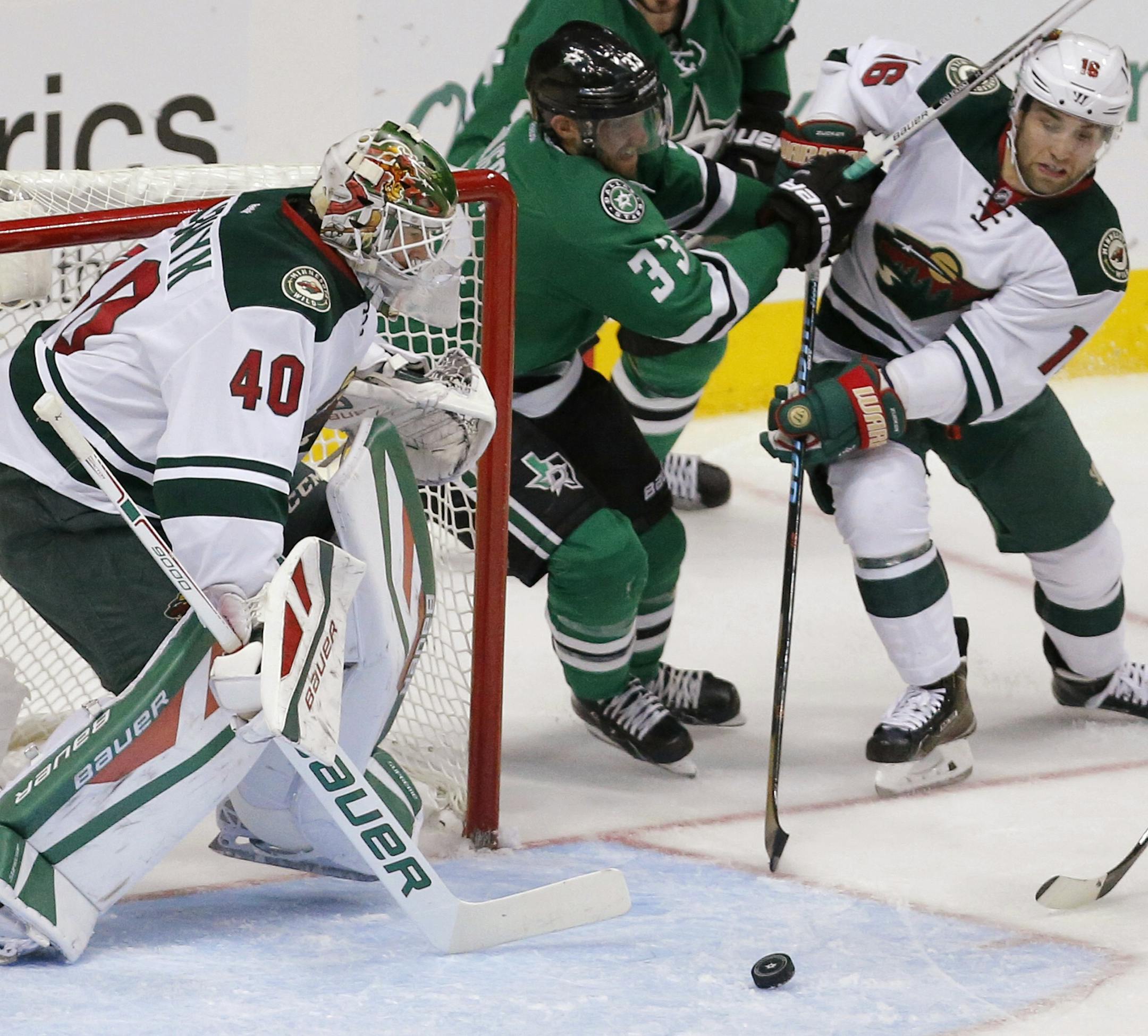 Minnesota Wild goalie Devan Dubnyk (40) watches as forward Jason Zucker (16) battles Dallas Stars defenseman Alex Goligoski (33) for control of the puck during the first period of an NHL hockey game, Saturday, Nov. 14, 2015, in Dallas. (AP Photo/Brandon Wade)