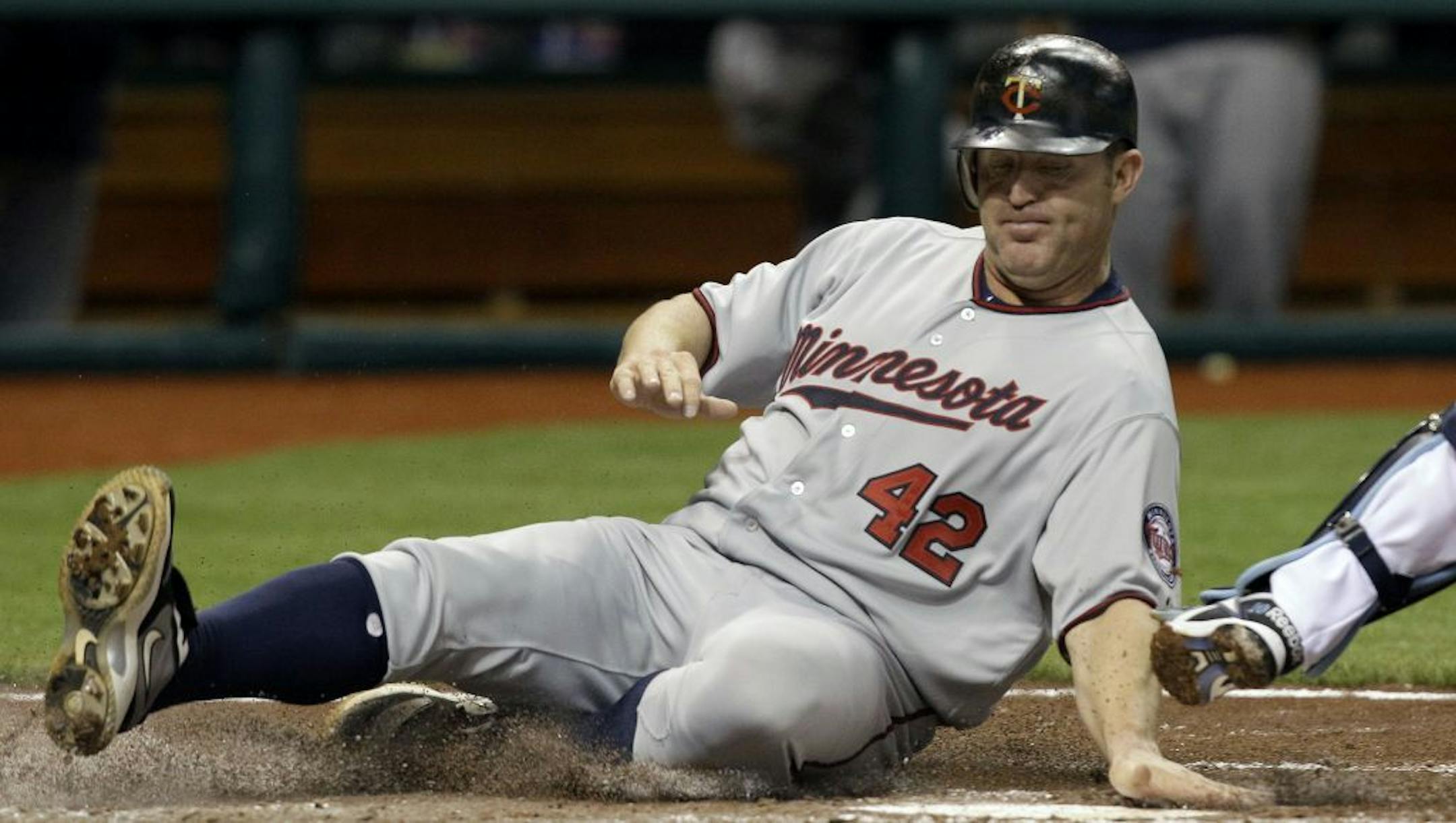 Minnesota Twins' Jim Thome slides around Tampa Bay Rays catcher Kelly Shoppach to score on a fifth inning double by teammate Danny Valencia during an MLB baseball game Friday, April 15, 2011 in St. Petersburg, Fla.