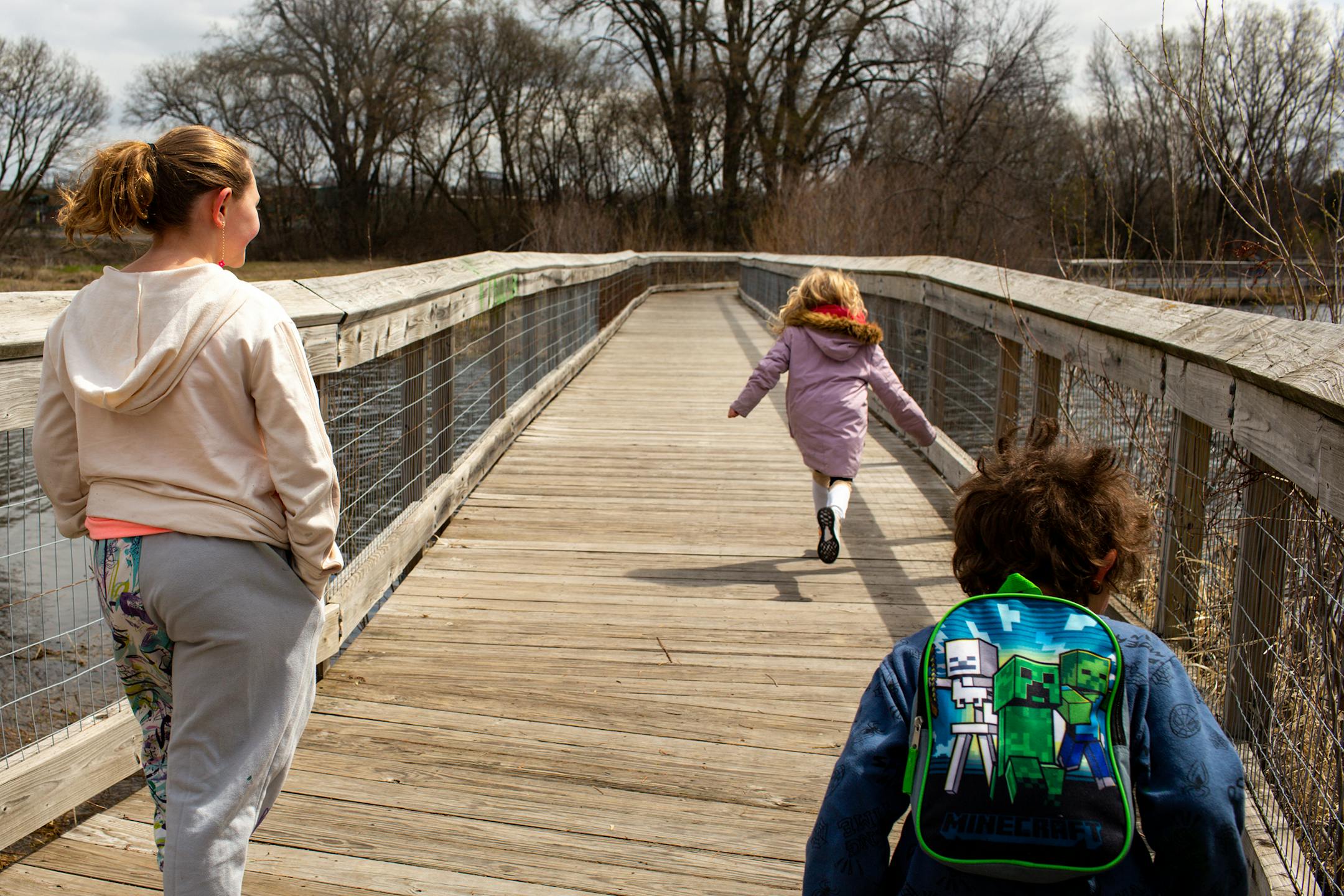 From left, Issabella Collins, 9, Frances Collins, 6, and Jordan Collins, 4, run down a walkway surrounding Keller Lake on Sunday, April 23, 2023, during a period of high spring flooding in Maplewood.