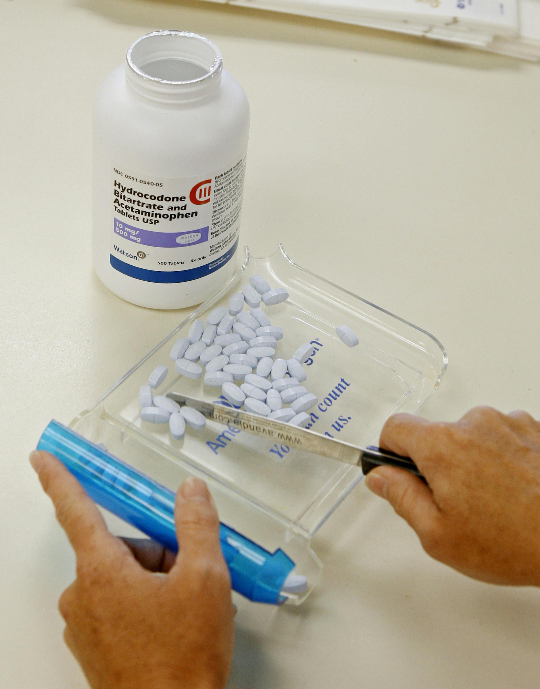 FILE - In this Aug. 5, 2010, file photo, a pharmacy technician poses for a picture with hydrocodone and acetaminophen tablets, also known as Vicodin, at the Oklahoma Hospital Discount Pharmacy in Edmond, Okla. Federal health regulators will bolster warning labels on the most widely used prescription painkillers, part of a multi-pronged federal effort to reverse an epidemic of abuse and death tied to drugs like Vicodin and Percocet, the FDA announced Tuesday, March 22, 2016. (AP Photo/Sue Ogrocki