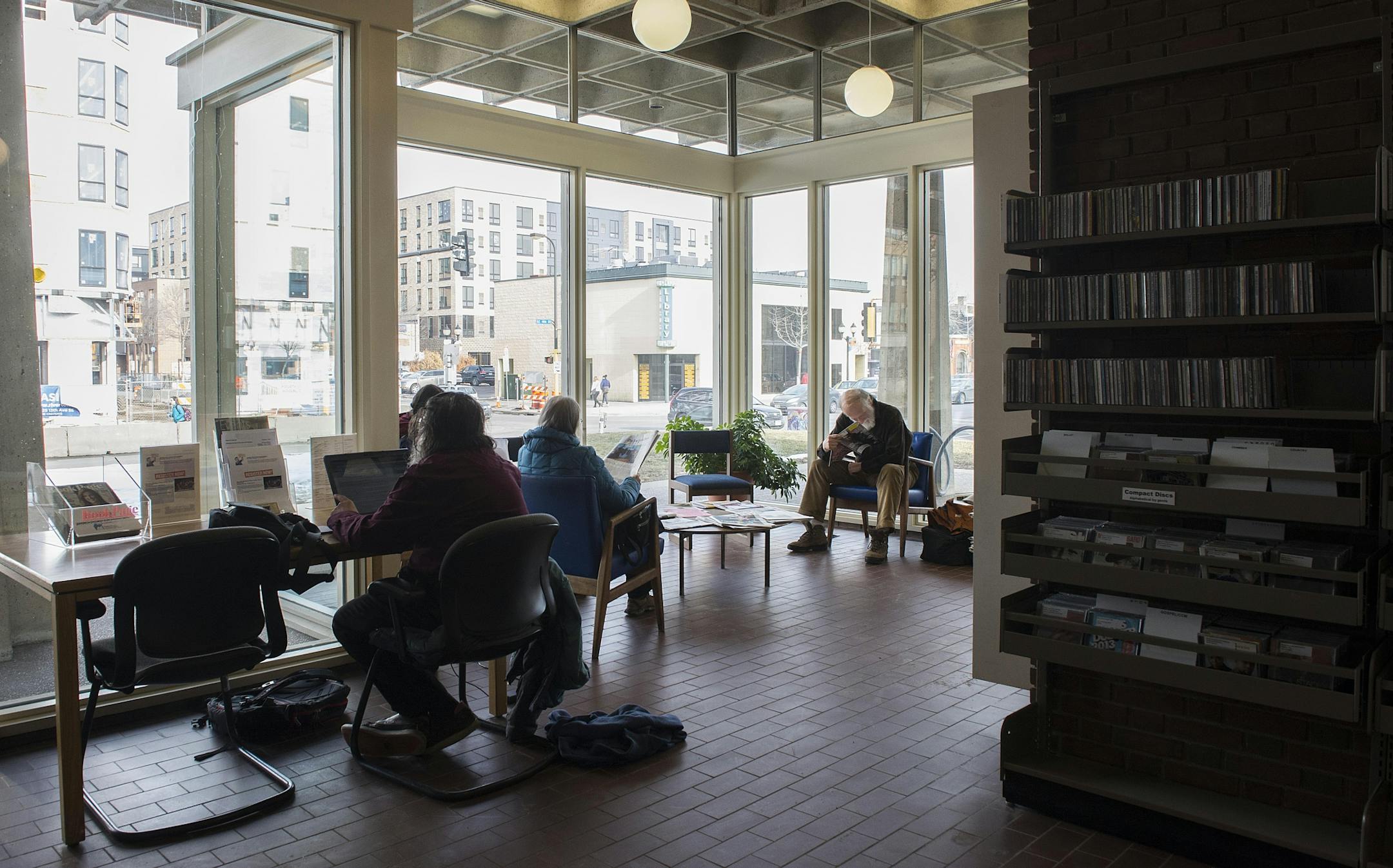 Southeast Library visitors read materials in a naturally lit corner of the library.
