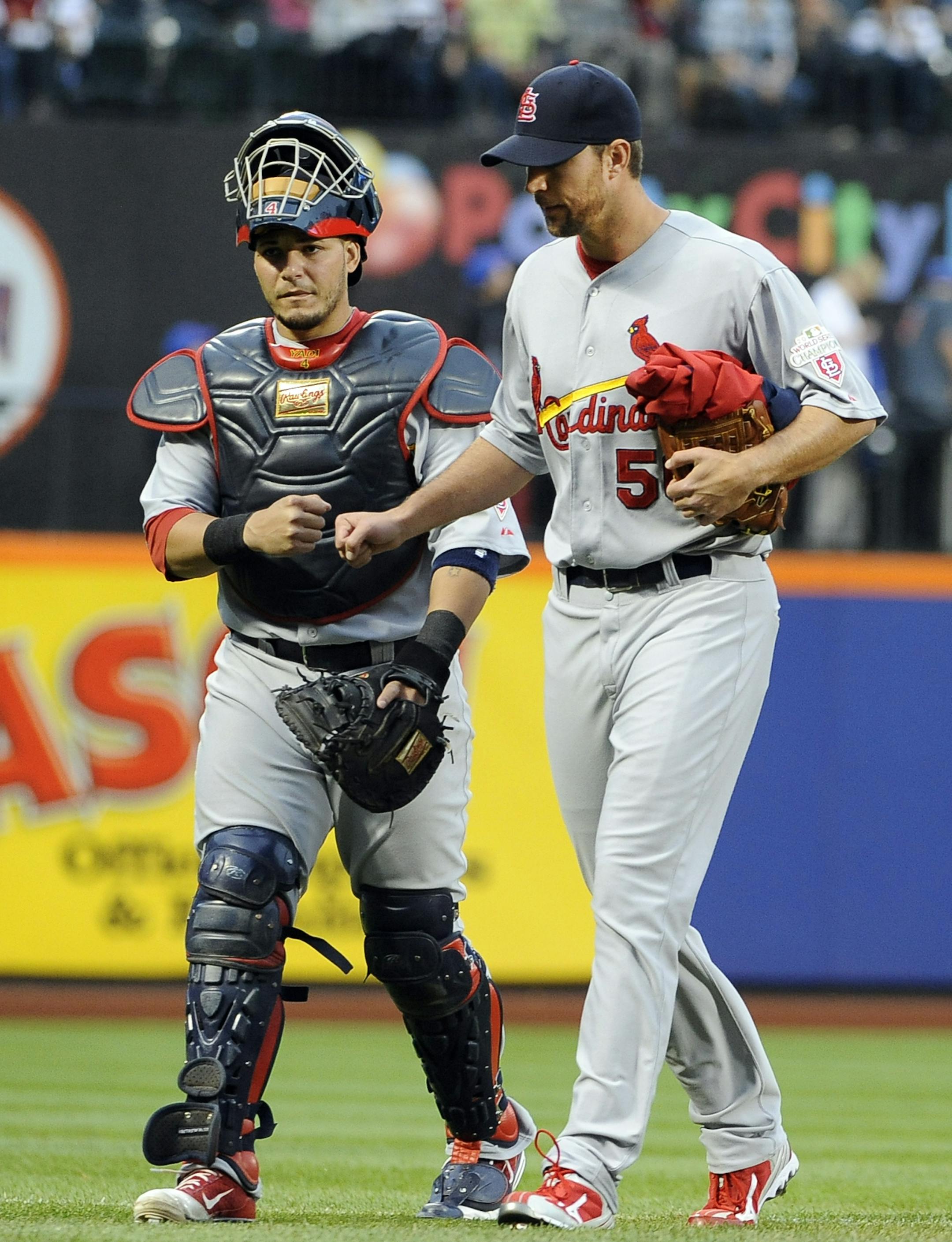St. Louis Cardinals catcher Yadier Molina punches fists with pitcher Adam Wainwright as he accompanies him to the dugout before the start of the baseball game against the New York Mets on Friday, June 1, 2012, at Citi Field in New York. (AP Photo/Kathy Kmonicek) ORG XMIT: NYOTK