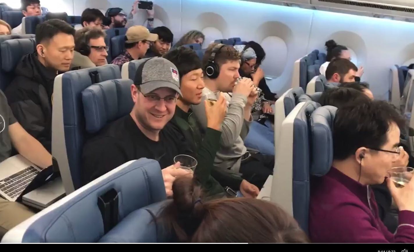 U.S. Men's Curling team skip John Shuster enjoys a champagne toast to the team's gold medal performance on the Delta flight home. Teammate Matt Hamilton (with mustache) is seated in the same row. This photo is a still from video tweeted by Star Tribune photographer Carlos Gonzalez, who was on the flight.