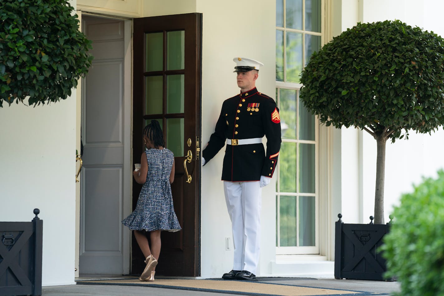 A Marine holds the door as Gianna Floyd, the daughter of George Floyd, walks into the White House, Tuesday, May 25, 2021, in Washington. (AP Photo/Evan Vucci)