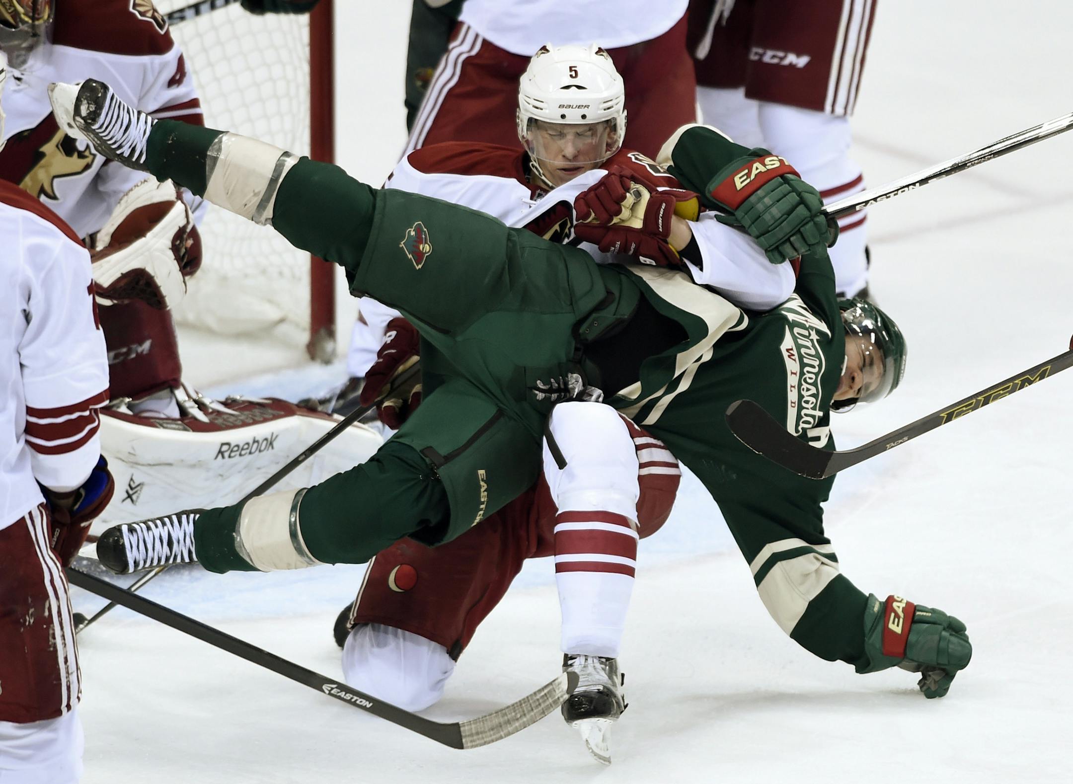 Arizona Coyotes defenseman Connor Murphy (5) and Minnesota Wild left wing Zach Parise (11) get tied up during the third period of an NHL hockey game Saturday, Jan. 17, 2015, in St. Paul, Minn. No penalties were called on the play. The Wild won 3-1. (AP Photo/Hannah Foslien)