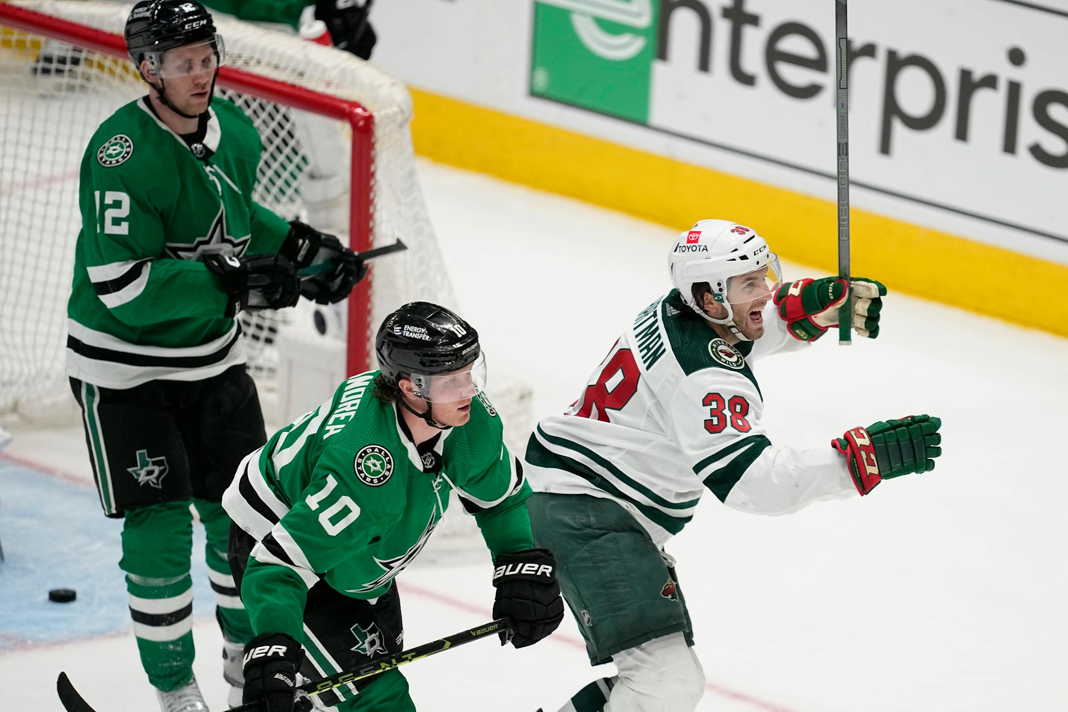 Minnesota Wild right wing Ryan Hartman (38) celebrates in front of Dallas Stars' Ty Dellandrea (10) and Radek Faksa (12) after scoring in the second overtime of Game 1.
