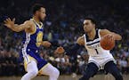 Golden State Warriors' Stephen Curry, left, defends against the Timberwolves' Tyus Jones on Friday. Jones missed the Wolves' previous game.