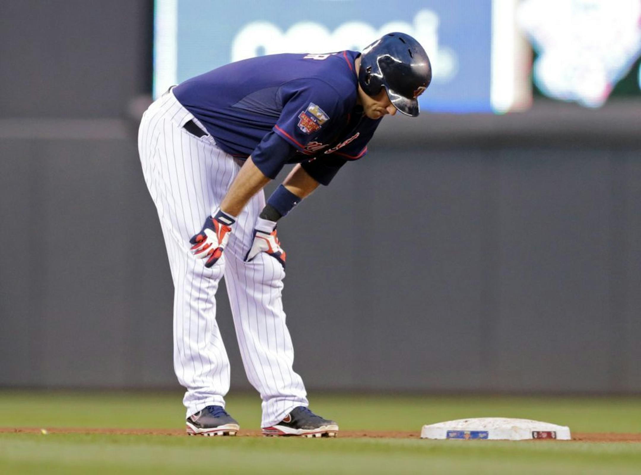 Minnesota Twins' Joe Mauer holds his legs after he pulled up to second with a two-run double off Kansas City Royals pitcher James Shields in the fourth inning of a baseball game, Tuesday, July 1, 2014, in Minneapolis. Mauer later left the game.