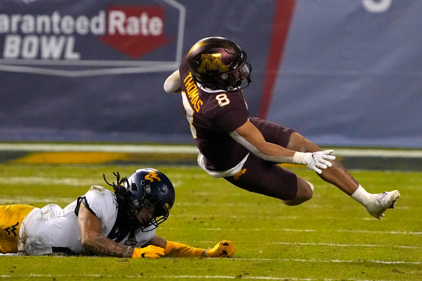 West Virginia cornerback Daryl Porter Jr. sends Minnesota running back Ky Thomas (8) to the turf during the first half of the Guaranteed Rate Bowl NCAA college football game Tuesday, Dec. 28, 2021, in Phoenix. (AP Photo/Rick Scuteri)