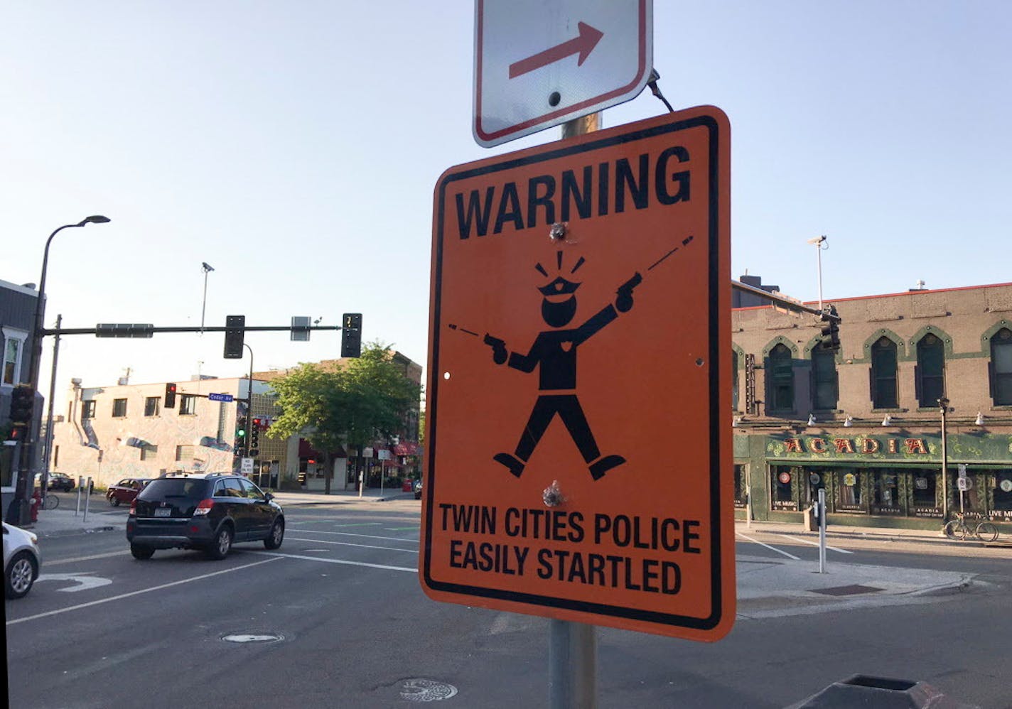 A fake street sign mounted on the same pole as two legitimate ones at the intersection of Cedar and Riverside Aves. Sunday evening in Minneapolis.