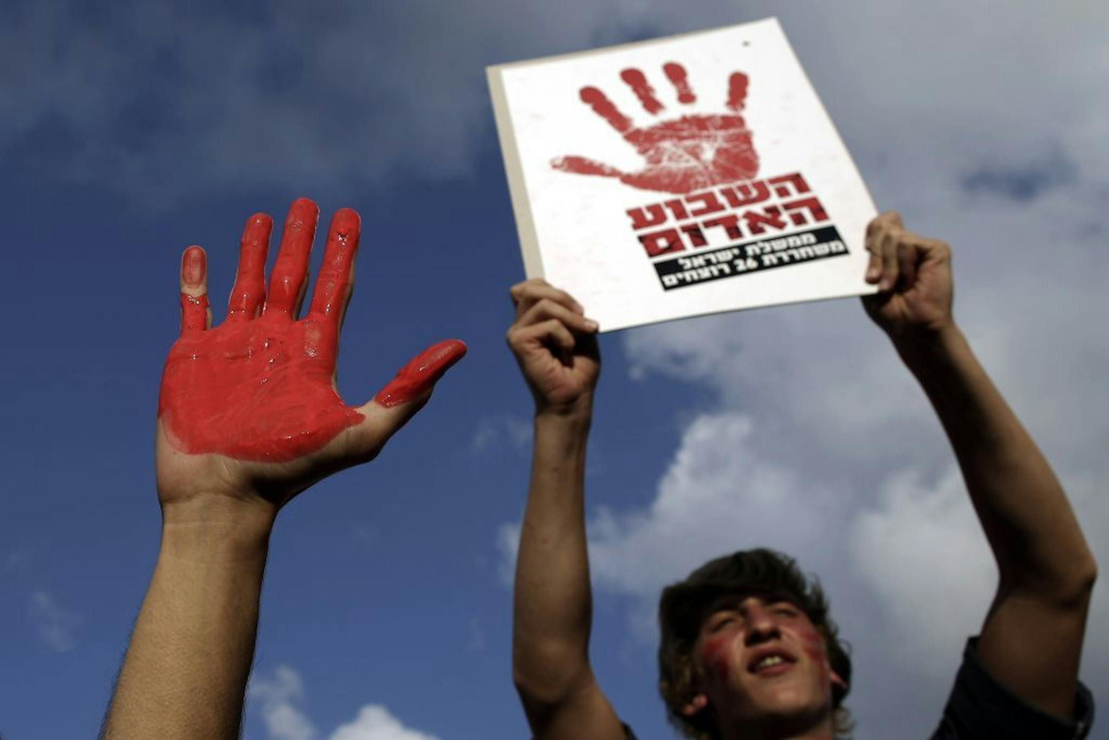 A man holds a sign which reads, "Red week, the Israeli government releases twenty six murderers," during a protest in Tel Aviv, Israel, Monday, Aug. 12, 2013.