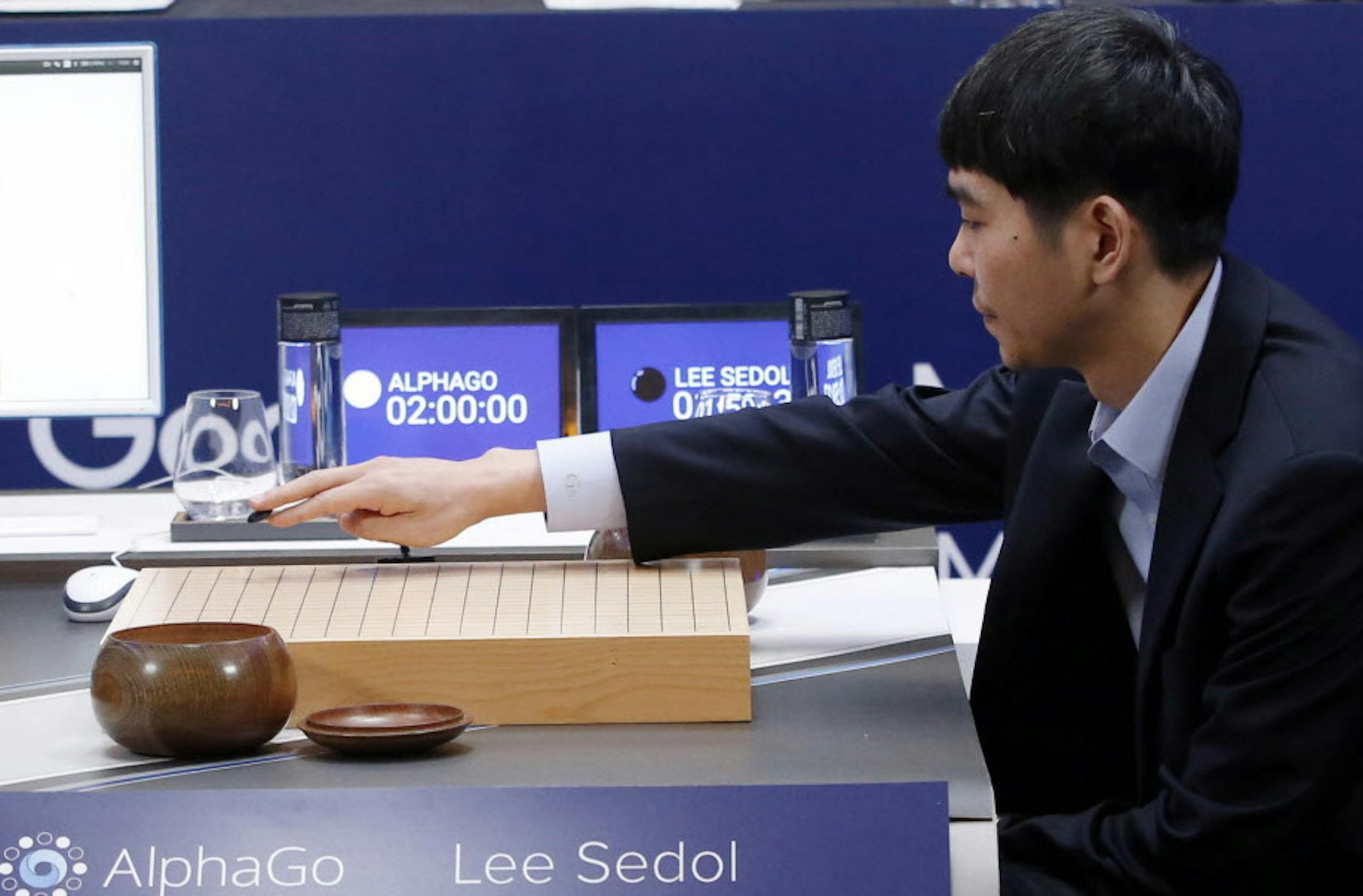 South Korean professional Go player Lee Sedol puts the first stone against Google's artificial intelligence program, AlphaGo, as Google DeepMind's lead programmer Aja Huang, left, sits during the final match of the Google DeepMind Challenge Match in Seoul, South Korea, Tuesday, March 15, 2016. A champion Go player scored his first win over a Go-playing computer program on Sunday after losing three straight times in the ancient Chinese board game, saying he finally found weaknesses in the softwar