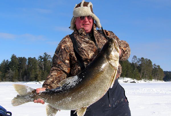 In this photo provided by Rob Scott and taken on Feb. 8, 2014, Rob Scott, of Crane Lake, Minn., poses with a 52-pound 3-ounce lake trout he caught whi
