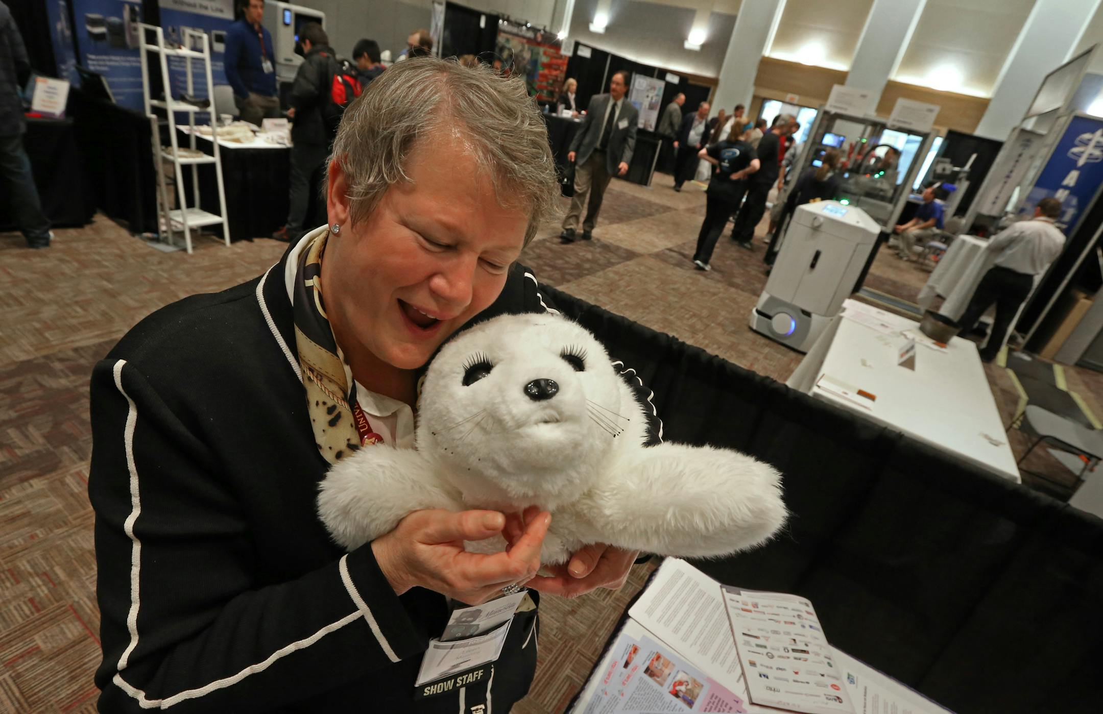 Eileen Manning, CEO of The Event Group, held a Paro, a therapeutic seal-like robot at the Robotics Alley Conference and Expo at the St. Paul River Center on 11/13/13. The therapy robot, that looks like a baby Harp seal, is made in Japan, responds to touch and is used hospitals and nursing homes.] Bruce Bisping/Star Tribune bbisping@startribune.com Eileen Manning/source.