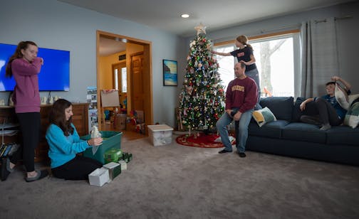 The Johnson family in their living room in Kenyon, Minn., on Dec. 10. While Talia, 14, and her mom Meredith unpacked Meredith’s Snow Baby collection, Ellie, 9, steadied herself on her father Ben’s head while she searched for an chocolate ornament to eat from the family Christmas tree. On the right is Frederick, 12.