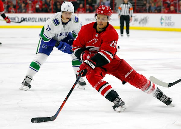 Carolina Hurricanes' Sebastian Aho (20) gathers in the puck in front of Vancouver Canucks' Nikolay Goldobin (77) during the second period of an NHL ho