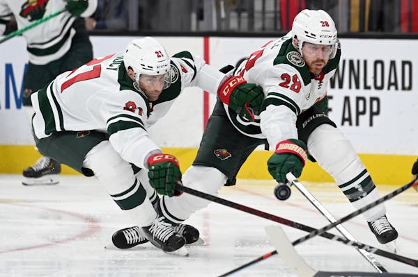 Wild defensemen Carson Soucy (21) and defenseman Ian Cole (28) reach for the puck during Game 2 in Las Vegas.