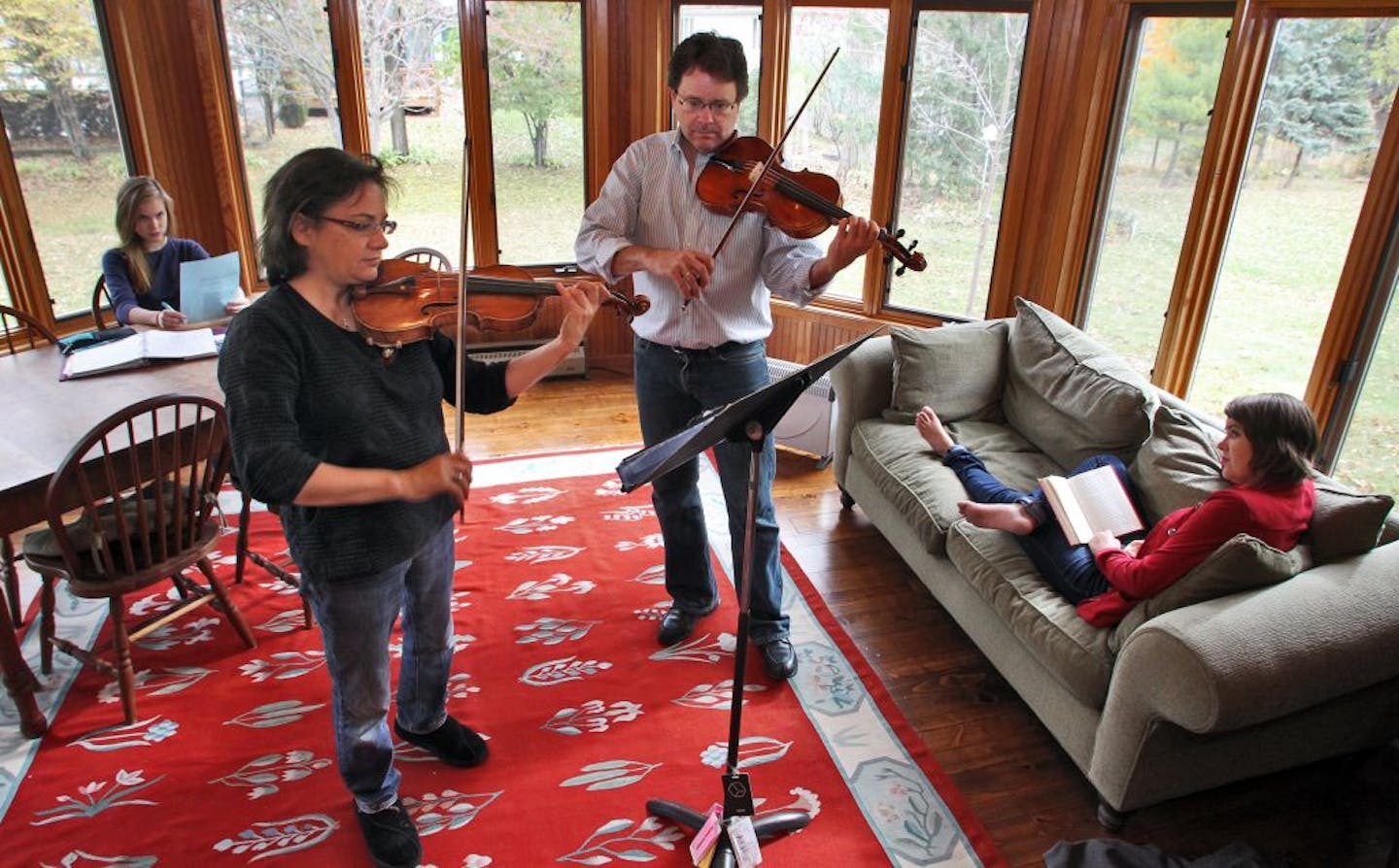 Daria and Michael Adams practiced in their Edina family room as daughters Tori, left, and Kiana studied. Daria is a violinist with the St. Paul Chamber Orchestra. Michael is a violist with the Minnesota Orchestra. Both organizations have locked out players in contract disputes.