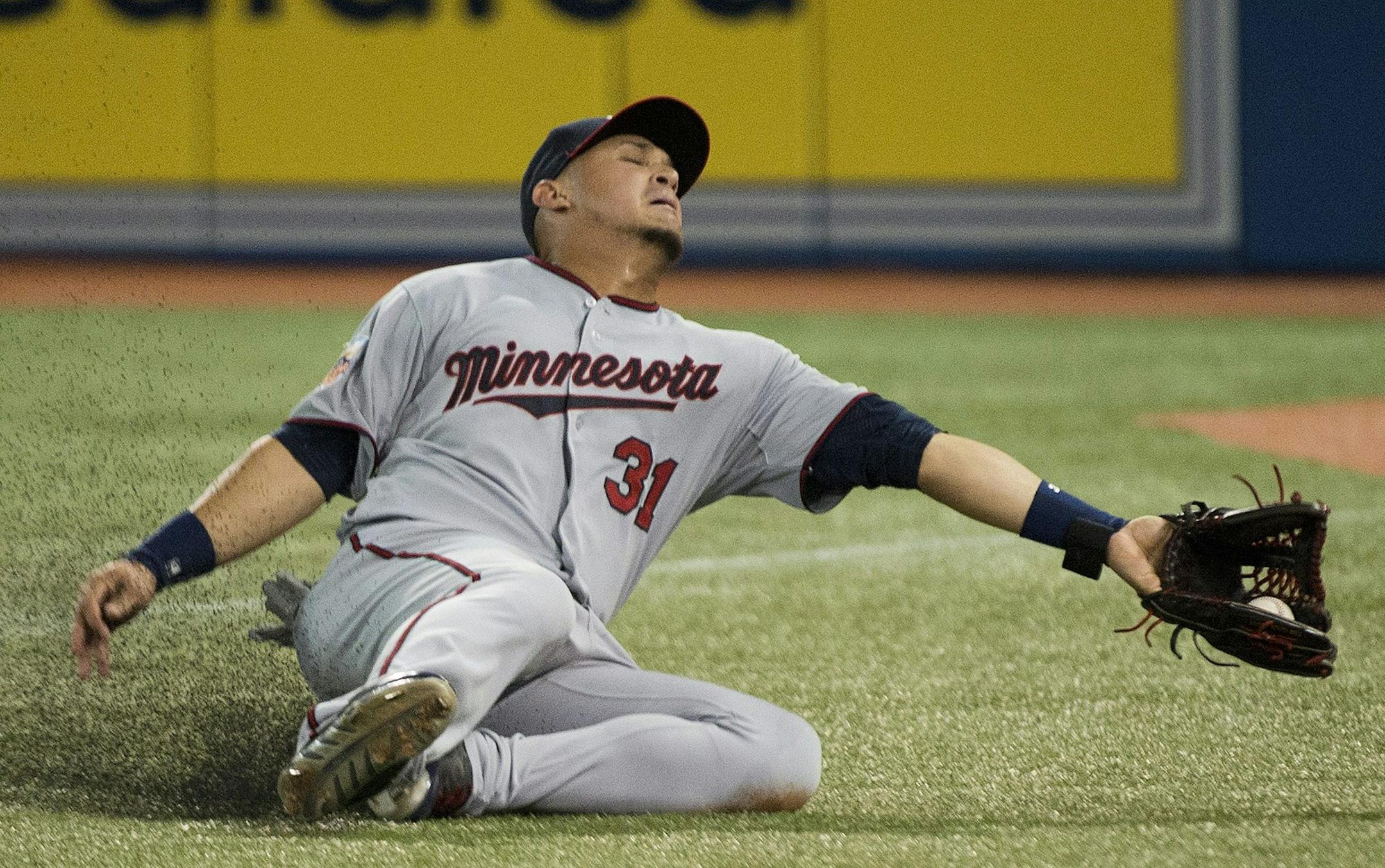 Minnesota Twins right fielder Oswaldo Arcia makes sliding catch on a ball hit by Toronto Blue Jays Jose Bautista during the sixth inning of a baseball game in Toronto on Wednesday, June 11, 2014. (AP Photo/The Canadian Press, Nathan Denette)