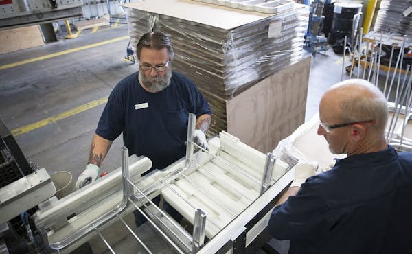Alexandria Industries' Brad Morgan, left, and Ed Schmidt, right, assemble solar rooftop racking-mounting systems at the central Minnesota plant.
