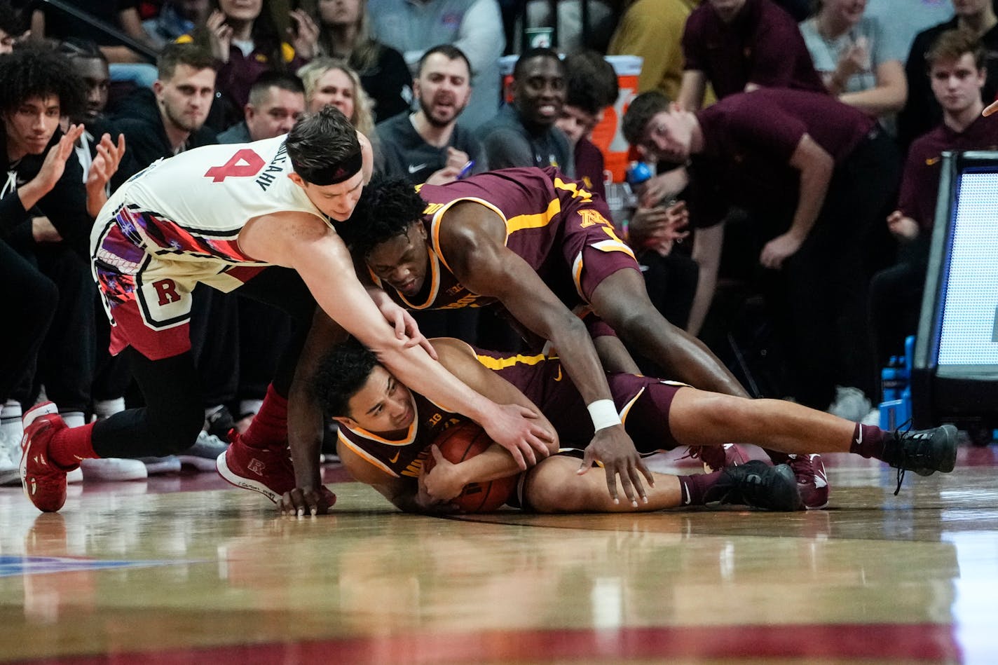 Rutgers' Paul Mulcahy, left, fights for control of the ball with Minnesota's Taurus Samuels, below, and Joshua Ola-Joseph, right, during the first half of an NCAA college basketball game, Wednesday, Feb. 1, 2023, in Piscataway, N.J. (AP Photo/Frank Franklin II)