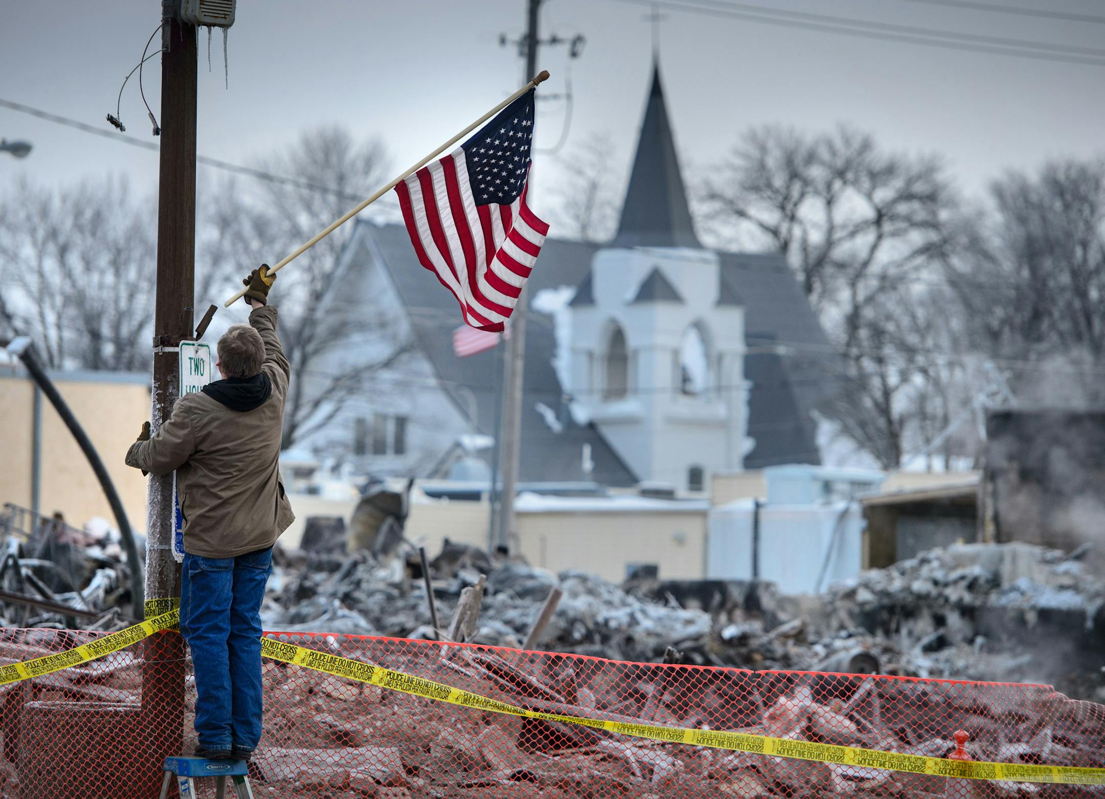 Madelia street supervisor Mark Elekestad hung American flags along Main Street in front of the block devastated by fire.
