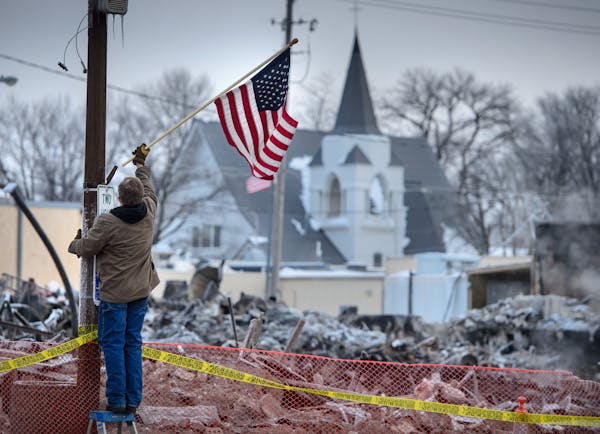 Madelia street supervisor Mark Elekestad hung American flags along Main Street in front of the block devastated by fire.